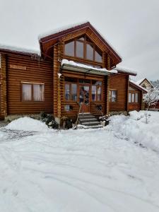 ein Blockhaus mit Schnee auf dem Boden in der Unterkunft Котедж в Карпатах in Skole
