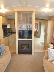 a living room with a fireplace with a tv at Barmouth Lyons Sunnysands 346 in Talybont