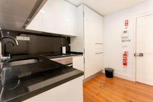 una cocina con armarios blancos y fregadero en Dockside Apartment by Innkeeper en Lisboa