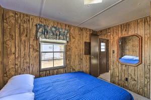 a bedroom with a blue bed and wooden walls at Pet-Friendly Cabin with Dock Fish and Explore! in Oriental