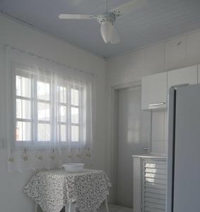 cocina blanca con mesa y ventilador de techo en Morada da Lena 1, en Balneário Camboriú
