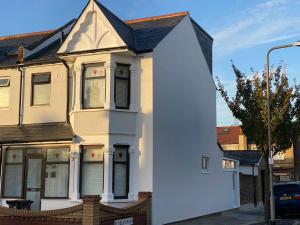 a white house with a black roof at Beautiful All room En-suite 4 bedrooms house , Free parking, WiFi, Corporate, Contractors, Family relocation, CONTACT US FOR LONG TERM RATE in Ilford