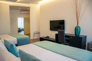 ein Hotelzimmer mit zwei Betten und einem Schreibtisch mit Fernseher in der Unterkunft 5ª Vigia in Porto de Mós + 66 Fotos