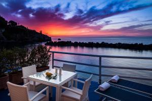uma mesa e cadeiras numa varanda com um pôr-do-sol em Ischia Blu Resort em Ischia