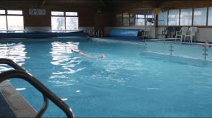 a person swimming in a large swimming pool at Barmouth Lyons Sunnysands 346 in Talybont