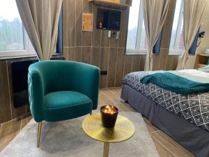 a room with a green chair and a table and a bed at Capsule Egypte - Jacuzzi - Sauna - Billard - Netflix & Home cinéma - Nintendo switch & jeu - in Crespin