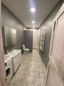 ein Bad mit einem Waschbecken und einem WC in der Unterkunft VODNA White Apartment in Lwiw