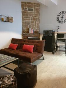 a living room with a brown couch with two red pillows at Suite privé dans maison de village in Soual