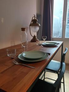 una mesa de madera con dos platos y vasos. en Suite privé dans maison de village, en Soual
