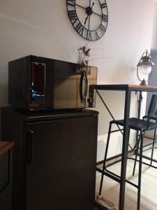 a microwave on top of a refrigerator with a table and a clock at Suite privé dans maison de village in Soual