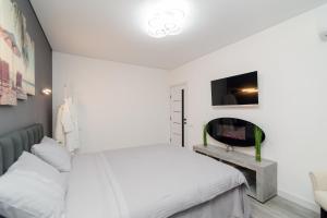 a white bedroom with a bed and a tv at Apartament Buiucani Alba Iulia in Chişinău