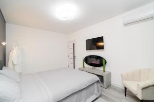 a white bedroom with a bed and a chair at Apartament Buiucani Alba Iulia in Chişinău