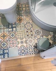 uma casa de banho com um WC e um piso com azulejos em Chambre studio indépendante au calme vue sur piscine em Teyran