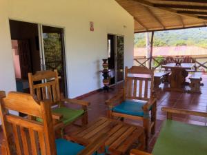 une terrasse couverte avec des chaises en bois, une table et des tables dans l'établissement Hotel Zaku Reserva Natural, à Palomino