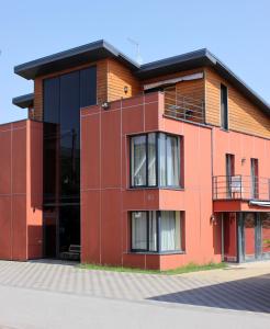 a red building with a balcony on a street at Jauku Erdvu Šilta in Kaunas