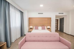 - une chambre avec un lit rose et un canapé rose dans l'établissement Hotel Ciudad de Ávila, à Ávila