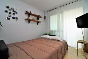 ein Schlafzimmer mit einem Bett, einem Fernseher und einem Fenster in der Unterkunft Trinisol Apartment Sea Views 6E Levante Beach in Benidorm