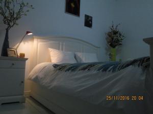 a bedroom with a white bed with a lamp and a night stand at Praça do Chile apartment in Lisbon
