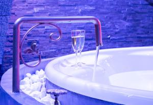 uma casa de banho com uma banheira e uma taça de champanhe em Cupidon Love Room em Vesoul