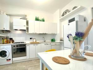 une cuisine avec des placards blancs et un vase de fleurs sur une table dans l'établissement CasaViva-Central Elegant apartment in Camogli, à Camogli