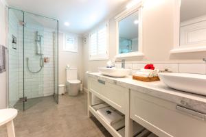 a white bathroom with two sinks and a shower at Hampton Court in Oneroa