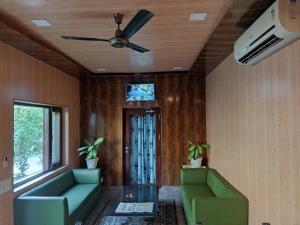 a living room with two green couches and a ceiling fan at Corbett Comfort Lodge in Garjia