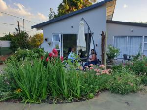 two women sitting outside of a house with flowers at Pine Park Garden Cottages in Johannesburg