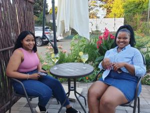 two women sitting at a table with glasses of wine at Pine Park Garden Cottages in Johannesburg