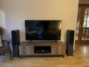a flat screen tv on a wooden entertainment center with speakers at Foxglove Cottages in Drymen