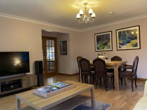 a living room with a dining room table and a television at Foxglove Cottages in Drymen