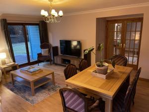 a living room with a wooden table and a television at Foxglove Cottages in Drymen