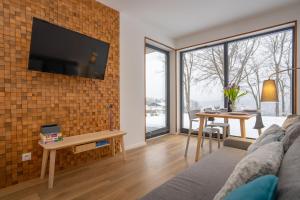 a living room with a couch and a tv on a brick wall at Karkonosky Apartamenty - Izery in Szklarska Poręba