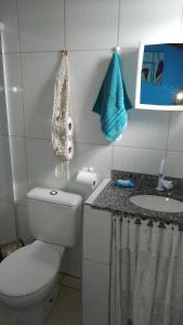 a white bathroom with a toilet and a sink at Hostel do Enzo in Itanhaém