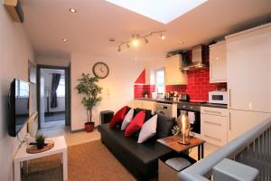 een woonkamer met een zwarte bank en een keuken bij Northcote Lane Apartments by Property Promise in Cardiff
