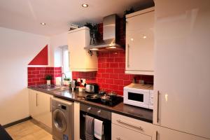 a kitchen with white cabinets and a red brick wall at Northcote Lane Apartments by Property Promise in Cardiff +13 photos