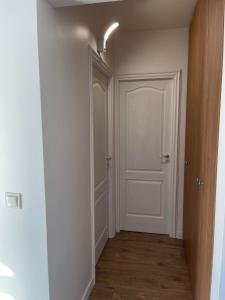 an empty hallway with a white door and wooden floors at Melissa Home in Vatra Dornei
