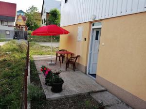un patio con una mesa y una sombrilla roja en Apartment Phillip, en Žabljak
