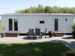 a patio with chairs and a table in front of a house at Tidy chalet with a microwave, near the Wadden Sea in Tzummarum