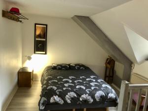 1 dormitorio con 1 cama con edredón blanco y negro en Appartement Cosy avec Balcon au calme proche Gare, en Bernay