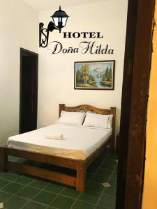 Una cama en una habitación con un cartel que lee hotel dolinulla en Hotel Doña Hilda, en San Martín
