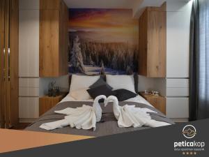 dos cisnes blancos están sentados en una cama en Apartman PETICA KOP A8 Kopaonik en Kopaonik
