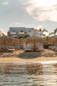a beach with benches and umbrellas next to the water at Calma Boutique Hotel in Posidhonía