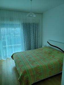 ein Schlafzimmer mit einem Bett mit einer grünen Decke und einem Fenster in der Unterkunft Apartman Petra in Budva