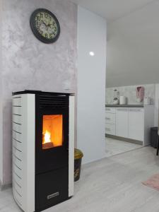 a fireplace in a kitchen with a clock on the wall at Apartman Nika in Pale