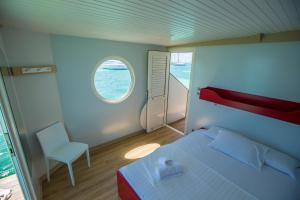 ein Schlafzimmer mit einem Bett, einem Fenster und einem Stuhl in der Unterkunft Aqualodge Martinique in Le Marin