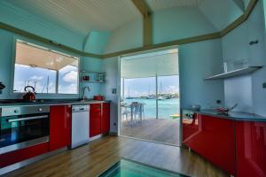 a kitchen with red cabinets and a view of the water at Aqualodge Martinique in Le Marin
