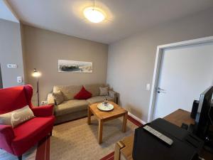 ein Wohnzimmer mit einem Sofa und einem roten Stuhl in der Unterkunft Muschelsucher in Westerland