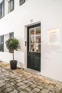 eine schwarze Tür in einem weißen Gebäude mit einem Topfbaum in der Unterkunft Meloussa Boutique Hotel in Ciutadella