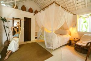 a woman in a bedroom with a canopy bed at Pousada Sol da Manha QUADRADO in Trancoso