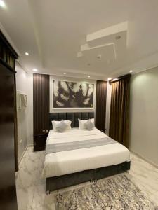 a bedroom with a large bed and a painting on the wall at Opera Suites in Muhayil